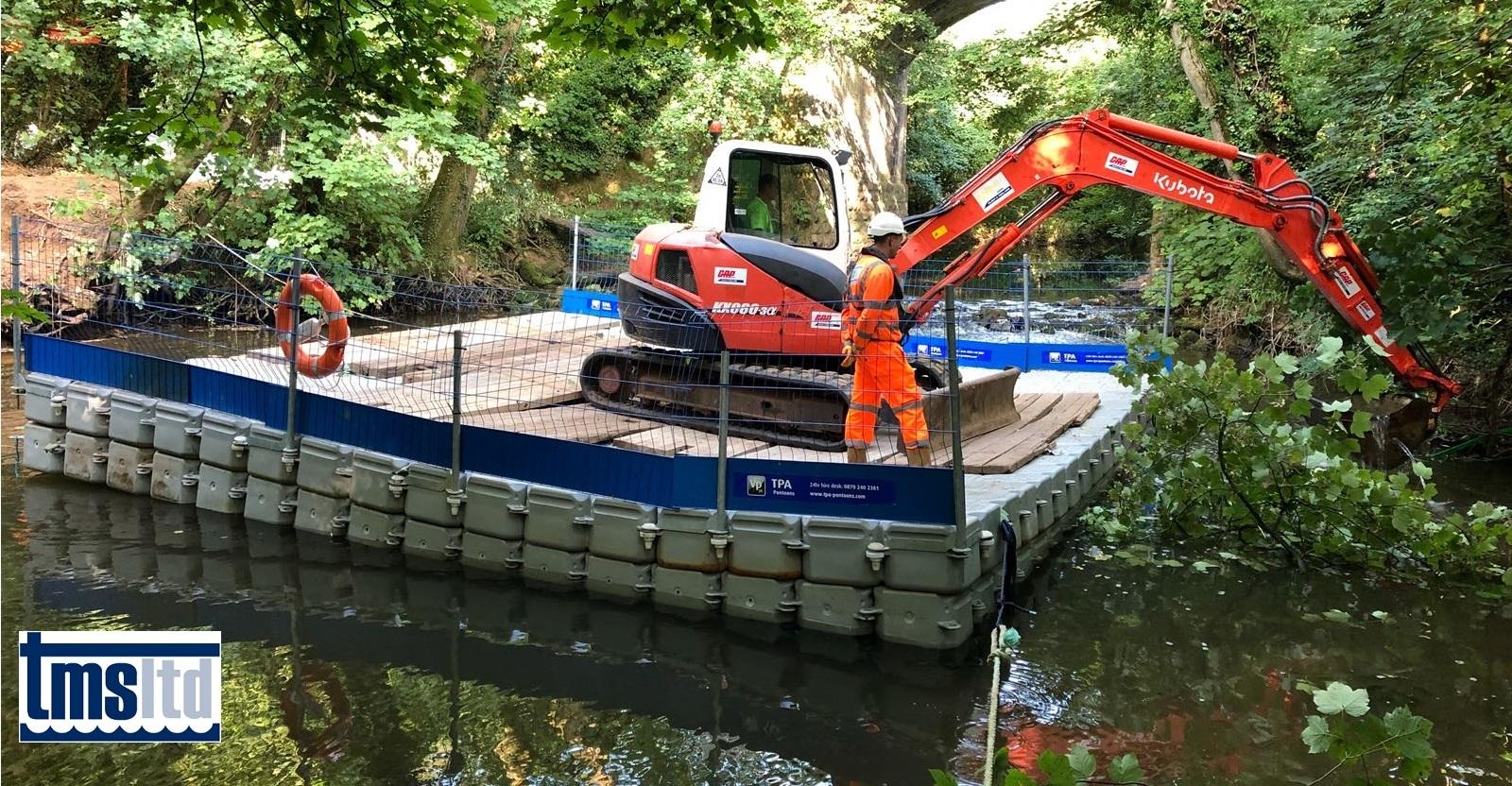 Digger working form raft in river at Newton St Cyres