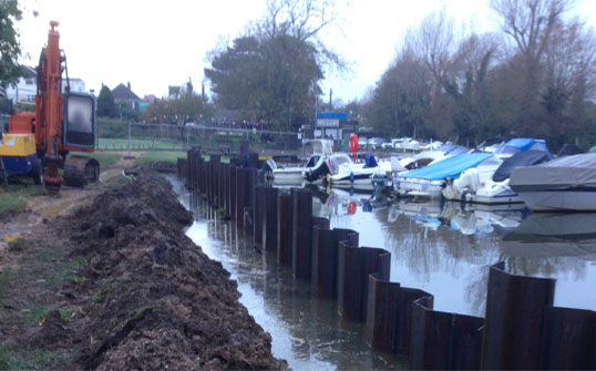 Boats in river as digger works from bank