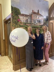 Three Women Standing Together One Is Holding A Balloon That Says Thank You